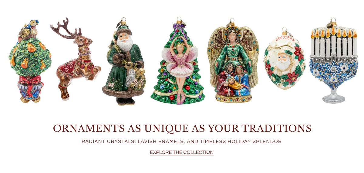 Collection banner titled "ORNAMENTS AS UNIQUE AS YOUR TRADITIONS" with subtitle "RADIANT CRYSTALS, LAVISH ENAMELS, AND TIMELESS HOLIDAY SPLENDOR", showcasing seven jeweled glass ornaments: partridge pear tree, prancing reindeer, green-robed Santa, Christmas tree ballerina, nativity angel with Holy Family, 2026 Santa egg ornament, and a blue and silver Hanukkah menorah.