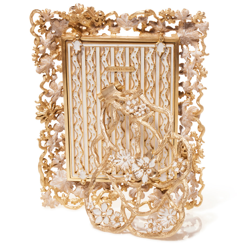 The Ophelia White Opal Picture Frame is just as exquisite from the back as it is from the front. Intricate 18k matte gold vines intertwine with delicate, hand-enameled ivory blossoms, creating a stunning sculptural design. A beautifully detailed gold-and-ivory patterned backing and ornate floral easel stand add elegance from every angle, making this frame a true work of art.