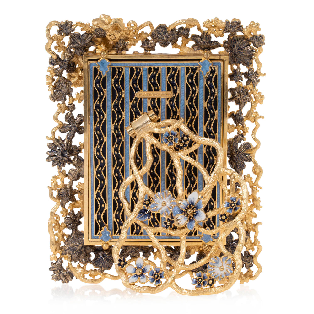 5" x 7" The back of this picture frame features an intricate gold-tone design with a deep navy-blue background accented by vertical blue enamel stripes and delicate gold vine patterns. An elaborate border of sculpted flowers and intertwining golden branches surrounds the rectangular frame, with blossoms in antique gold, dark bronze, and soft blue. The hinged easel stand resembles a graceful tangle of golden vines adorned with delicate blue enamel flowers and sparkling crystal centers