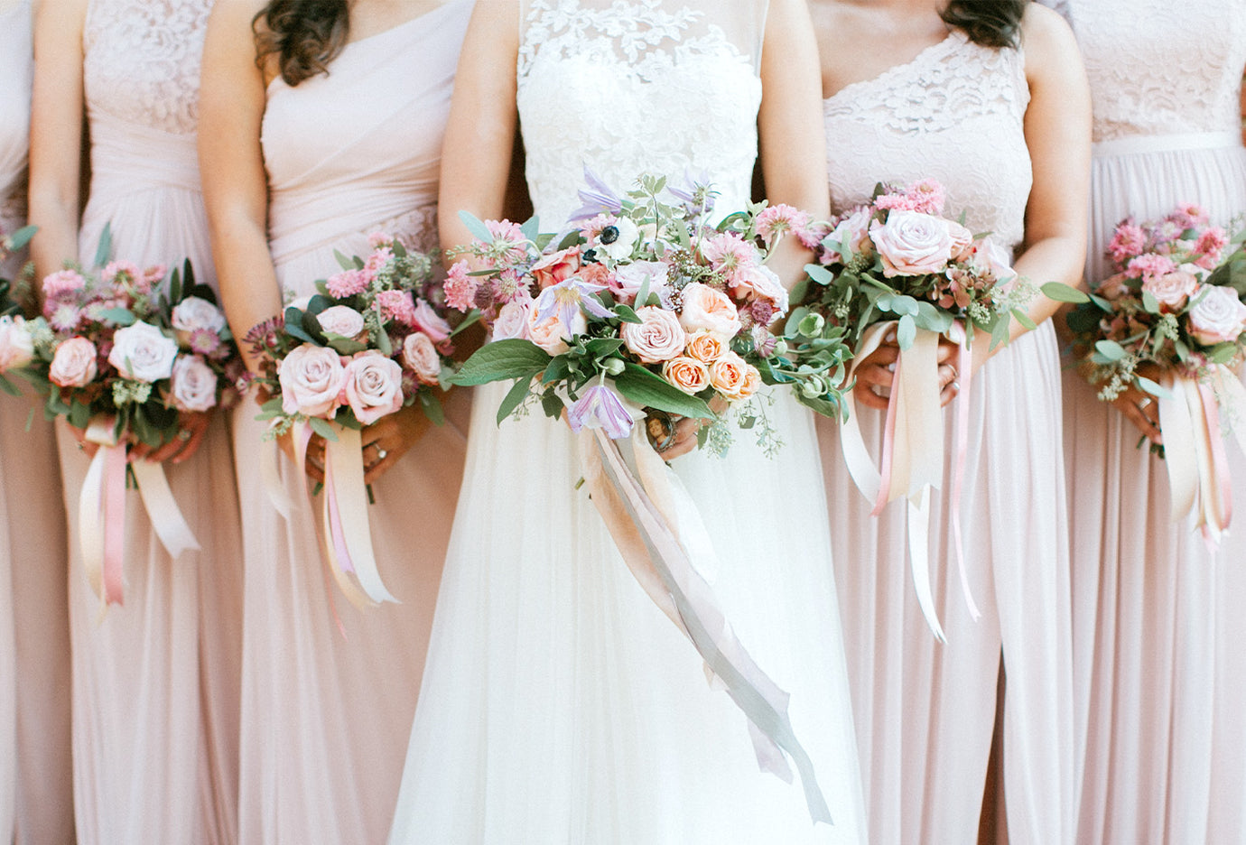 A line of bridesmaids holding a bouquet of flowers